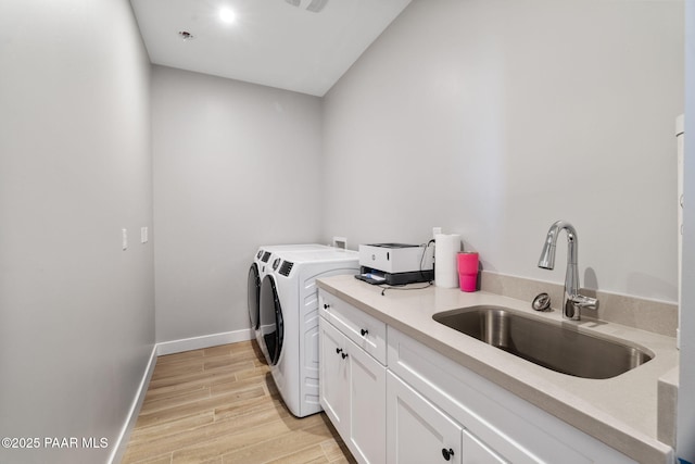 laundry room with washing machine and dryer, sink, and light wood-type flooring