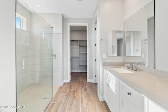 bathroom featuring hardwood / wood-style floors, vanity, and a tile shower