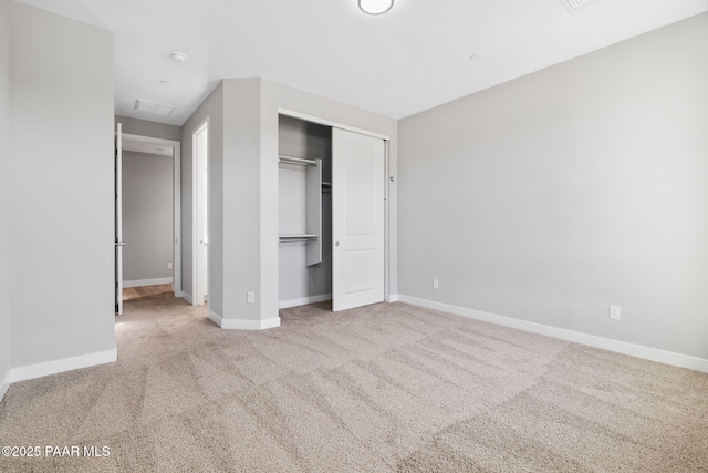 unfurnished bedroom with light colored carpet and a closet