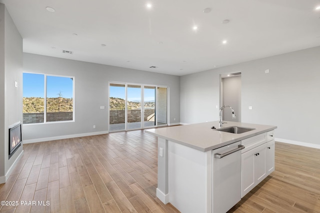 kitchen featuring white cabinetry, sink, a center island with sink, and stainless steel dishwasher