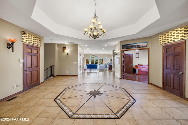 entrance foyer with light tile patterned flooring, a raised ceiling, and a chandelier