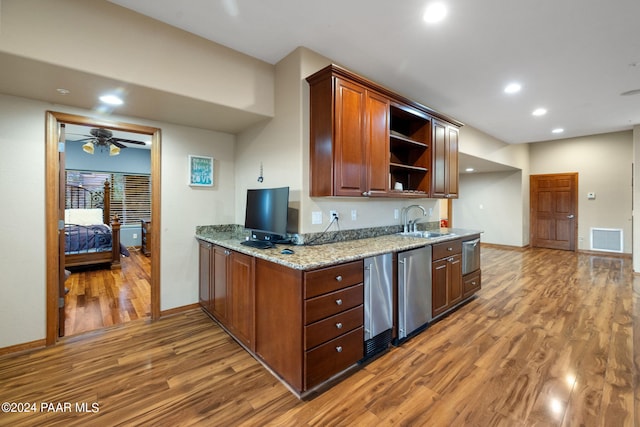 kitchen with light stone countertops, dishwasher, sink, ceiling fan, and wood-type flooring