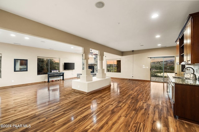 unfurnished living room featuring dark hardwood / wood-style flooring, ceiling fan, and sink