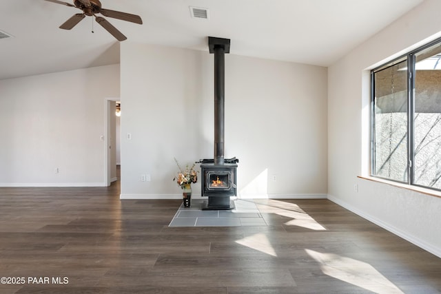 unfurnished living room with dark hardwood / wood-style floors, a wood stove, ceiling fan, and lofted ceiling