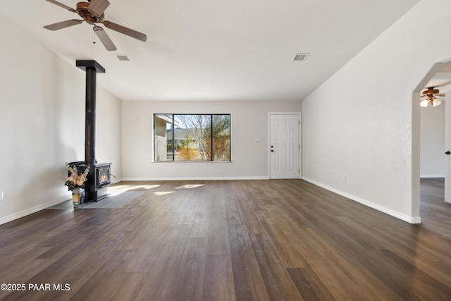 unfurnished living room with a wood stove, ceiling fan, and dark hardwood / wood-style flooring