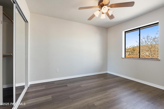 unfurnished bedroom featuring ceiling fan, a closet, and dark wood-type flooring