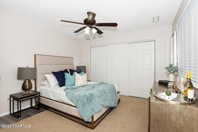 bedroom with ceiling fan, dark wood-type flooring, and a closet