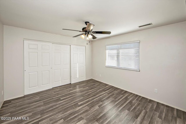 unfurnished bedroom featuring ceiling fan, dark hardwood / wood-style floors, and a closet