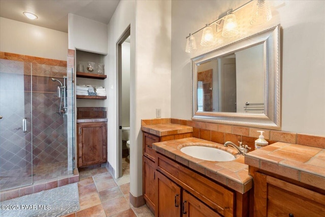 bathroom with a shower with door, vanity, and toilet