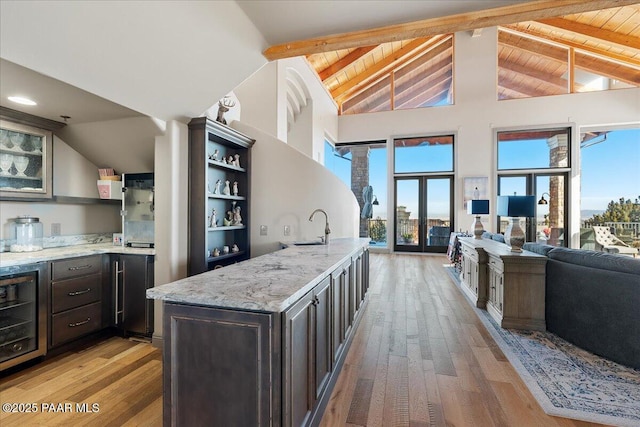 kitchen with beamed ceiling, wood ceiling, beverage cooler, and light stone counters