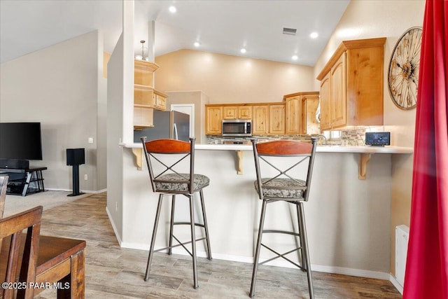 kitchen featuring a peninsula, a kitchen breakfast bar, visible vents, and appliances with stainless steel finishes