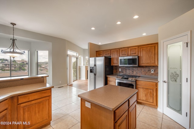 kitchen with hanging light fixtures, light tile patterned floors, tasteful backsplash, a kitchen island, and appliances with stainless steel finishes