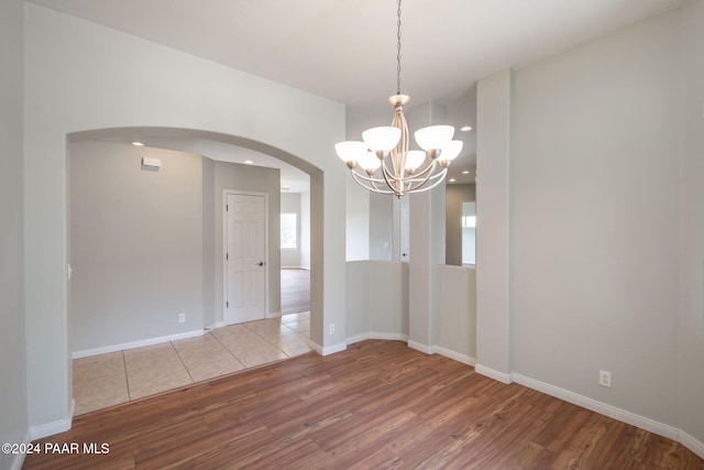 spare room featuring hardwood / wood-style floors and a notable chandelier