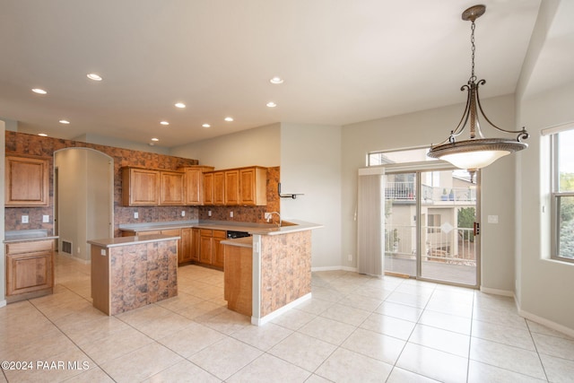 kitchen with sink, a kitchen island, decorative light fixtures, decorative backsplash, and light tile patterned floors