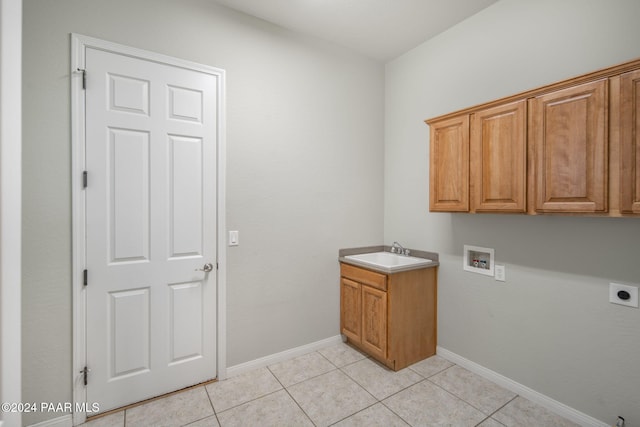 washroom with electric dryer hookup, sink, light tile patterned flooring, and cabinets