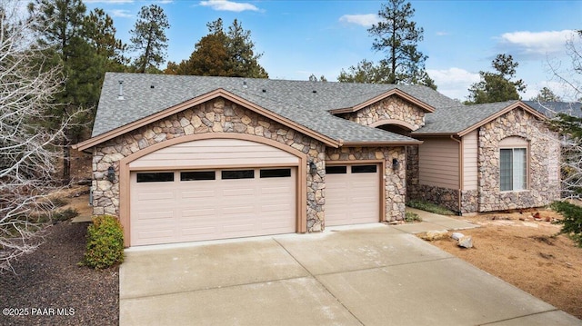 view of front of property with stone siding, roof with shingles, concrete driveway, and an attached garage