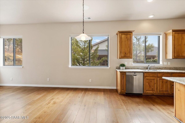 kitchen with light wood-style flooring, a sink, decorative light fixtures, stainless steel dishwasher, and brown cabinetry