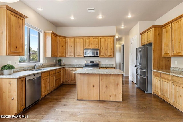 kitchen with a kitchen island, stainless steel appliances, wood finished floors, and a sink