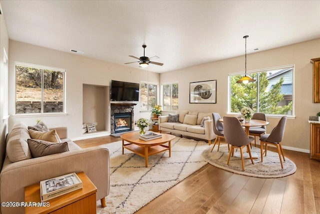 living room with visible vents, a ceiling fan, wood finished floors, a fireplace, and baseboards