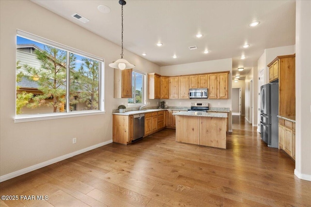 kitchen with visible vents, a center island, stainless steel appliances, light wood finished floors, and baseboards