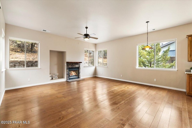 unfurnished living room with visible vents, a healthy amount of sunlight, ceiling fan, and hardwood / wood-style flooring