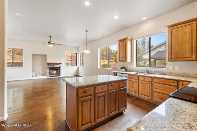 kitchen with hardwood / wood-style floors, light stone countertops, a sink, ceiling fan, and a center island