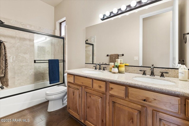 full bathroom featuring enclosed tub / shower combo, toilet, wood finished floors, and a sink