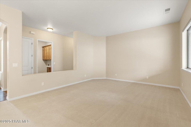 empty room with visible vents, baseboards, and carpet