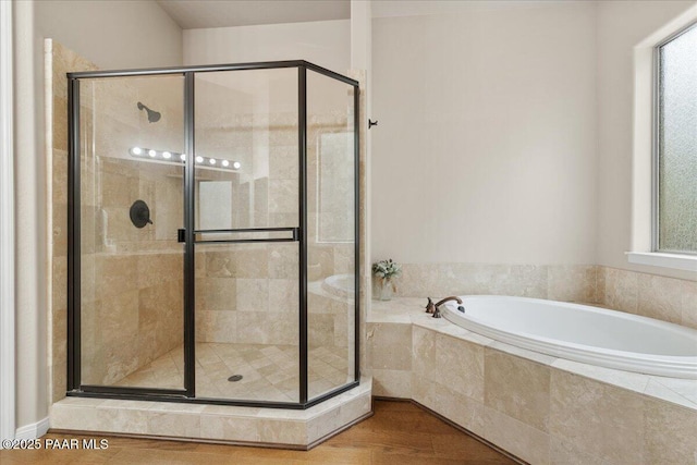 bathroom featuring a bath, a shower stall, and wood finished floors