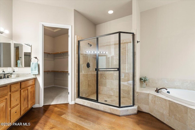 bathroom featuring vanity, a shower stall, a spacious closet, and wood finished floors