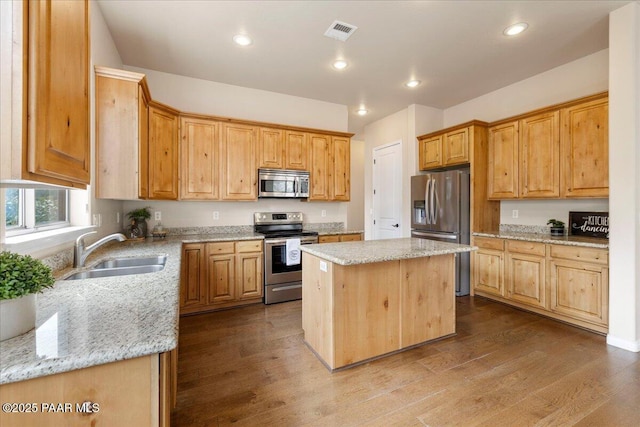 kitchen with visible vents, a sink, light stone counters, dark wood finished floors, and appliances with stainless steel finishes