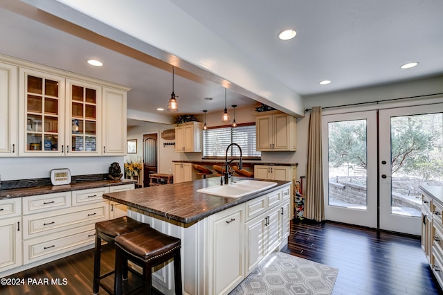 kitchen with sink, pendant lighting, a center island with sink, dark hardwood / wood-style floors, and a breakfast bar area