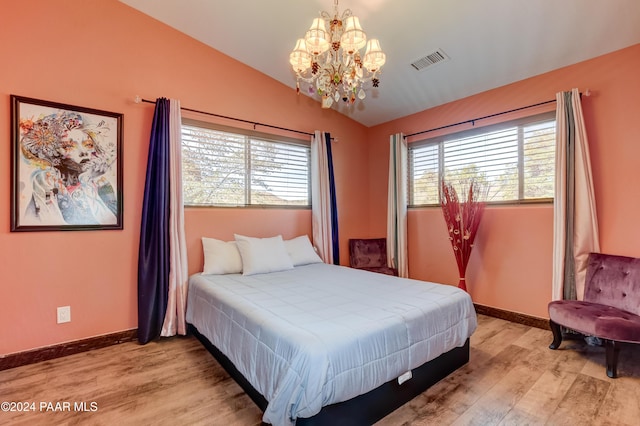 bedroom featuring light hardwood / wood-style floors, an inviting chandelier, and lofted ceiling