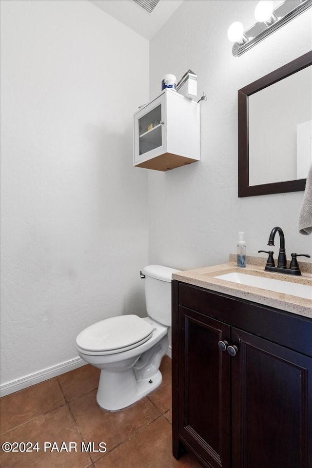 bathroom with toilet, vanity, and tile patterned floors