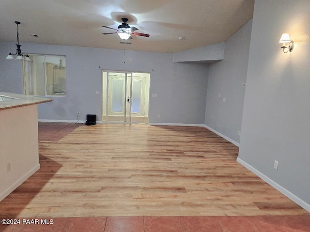 unfurnished living room featuring light hardwood / wood-style flooring and ceiling fan with notable chandelier