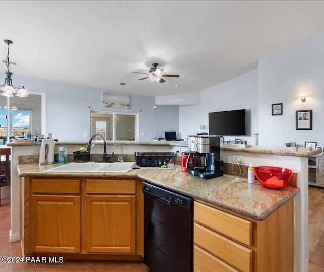 kitchen with light stone counters, ceiling fan with notable chandelier, sink, pendant lighting, and black dishwasher