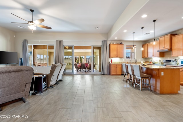 kitchen featuring stainless steel electric range oven, a kitchen island, a breakfast bar area, and open floor plan