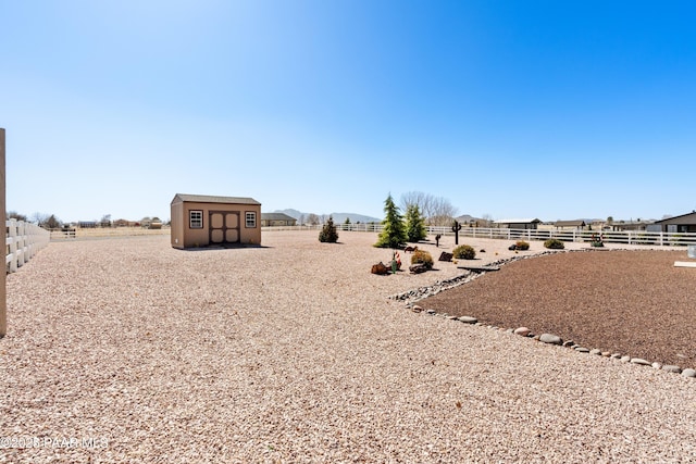 view of yard featuring an outbuilding, fence, and a storage unit