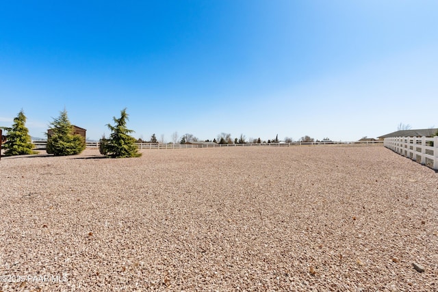 view of yard featuring an enclosed area, a rural view, and fence