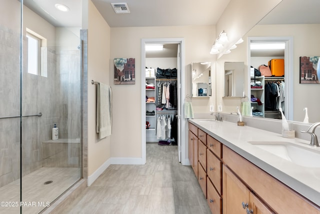 bathroom featuring visible vents, a sink, a tile shower, and double vanity