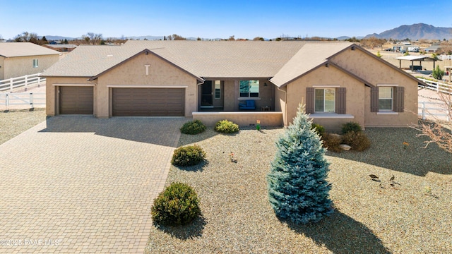 view of front facade featuring a garage, decorative driveway, fence, and stucco siding