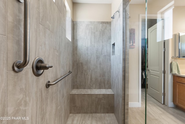 bathroom with tiled shower and vanity