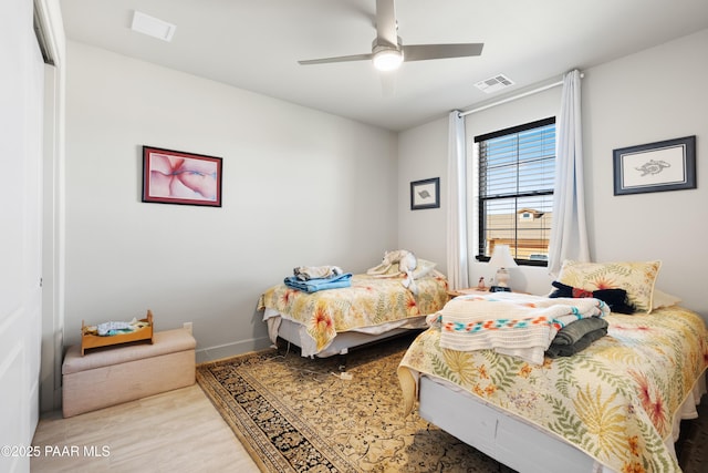 bedroom with ceiling fan, wood finished floors, visible vents, and baseboards