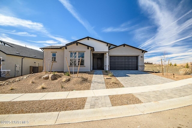 single story home featuring an attached garage, decorative driveway, and stucco siding