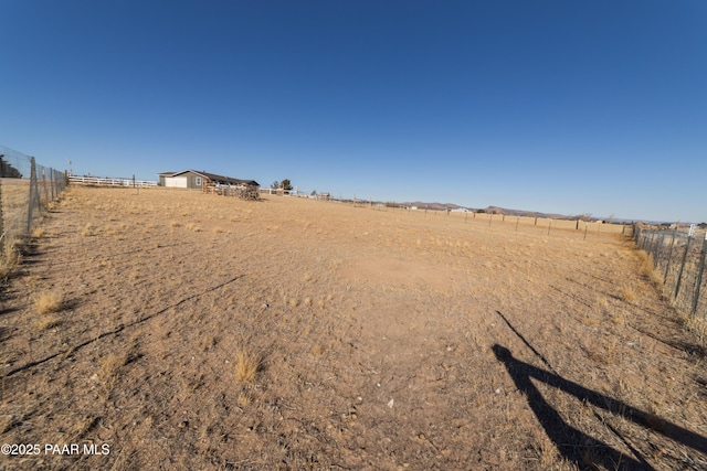 view of yard with fence and a rural view