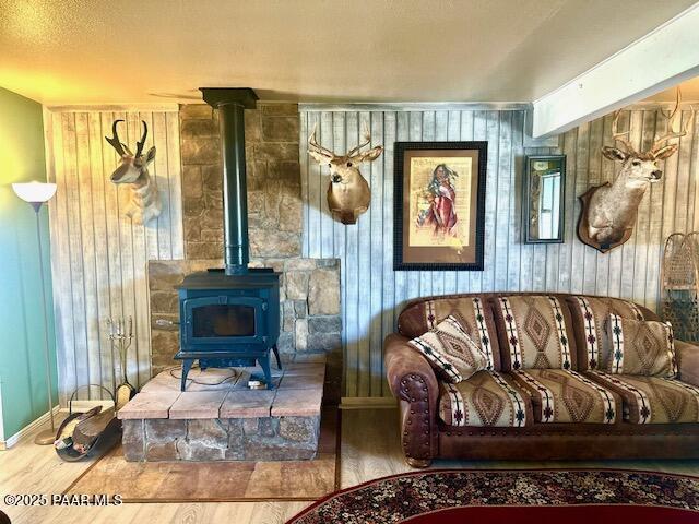 living area with wood walls, wood finished floors, a wood stove, and baseboards