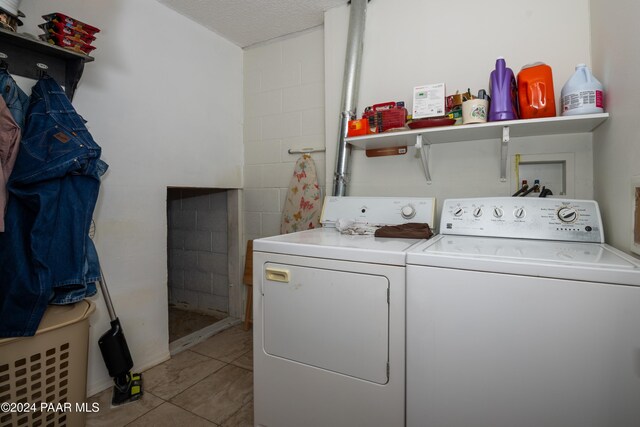 clothes washing area with light tile patterned floors, washer and dryer, and a textured ceiling