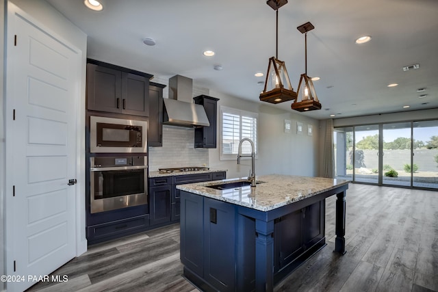 kitchen with wall chimney exhaust hood, a wealth of natural light, sink, and appliances with stainless steel finishes