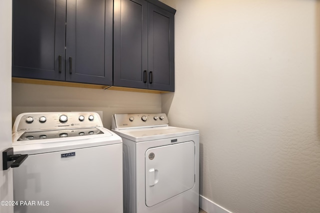 laundry area with washing machine and dryer and cabinets