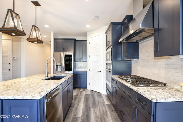 kitchen with appliances with stainless steel finishes, sink, wall chimney range hood, pendant lighting, and dark hardwood / wood-style floors